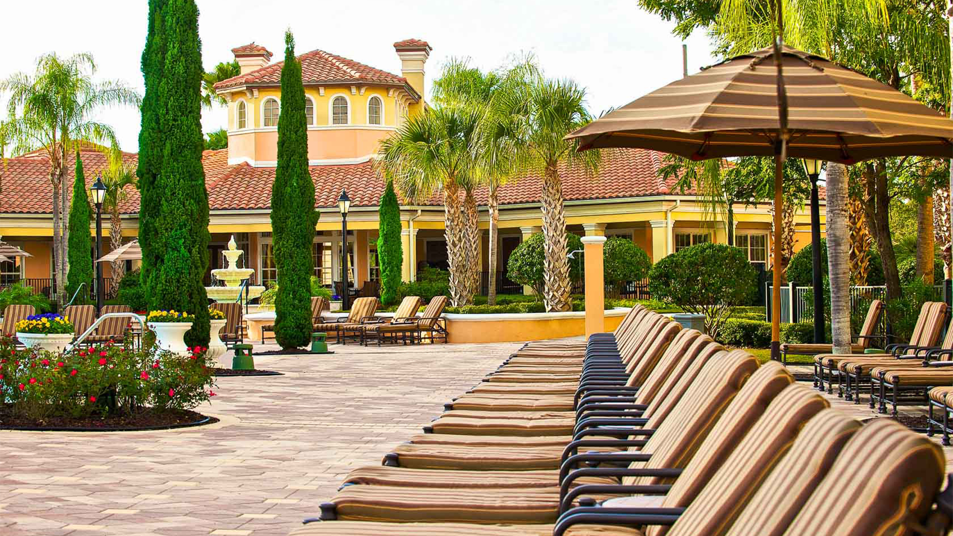 a patio with pool chairs and umbrellas